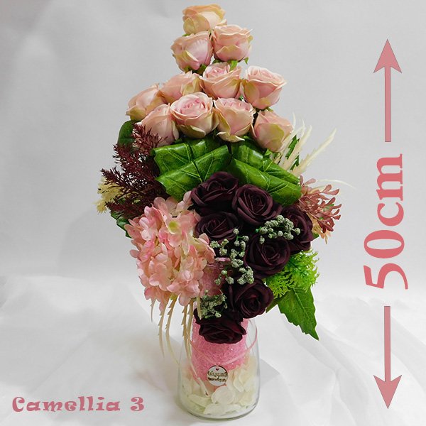 Camellia vase bouquet in transparent glass with optimistic artificial blooms