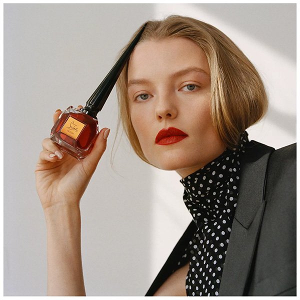 Leather Perfume Cuir Fétiche held by model with red lipstick and polka dot blouse