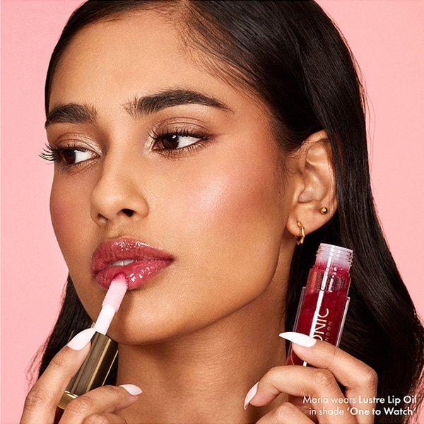 Lip Oil ICONIC LONDON Lustre One To Watch being applied to glossy lips with chunky doe-foot applicator